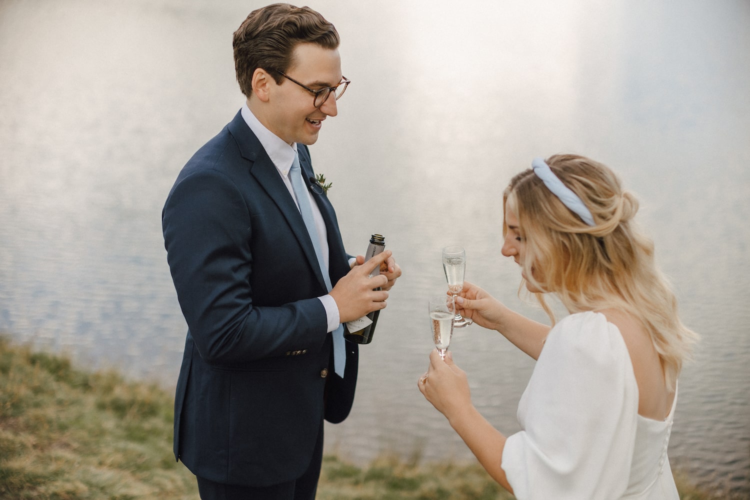 couple popping champagne in Bachalpsee after their wedding ceremony